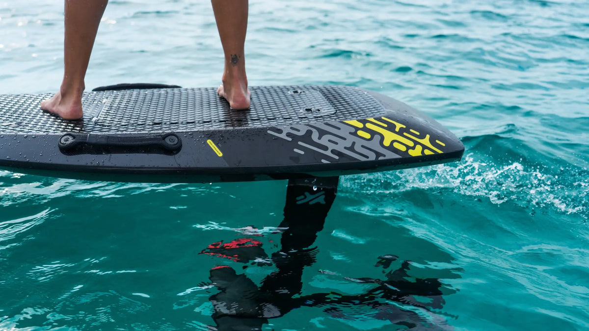 Close-up of an Aerofoils eFoil board flying just above turquoise water, with the mast and wing below the surface